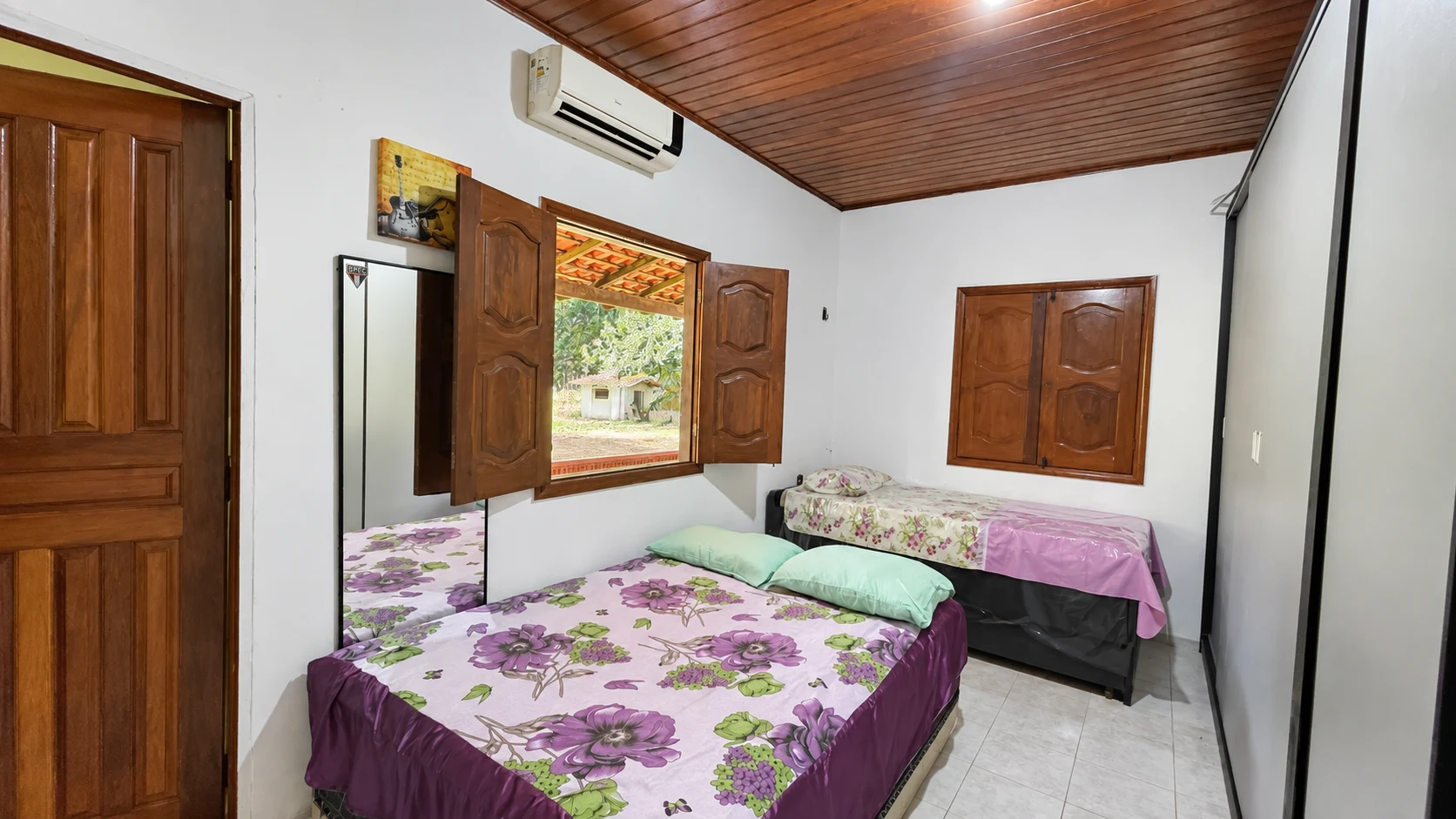 Quarto da casa com cama de casal, cama de solteiro e armários