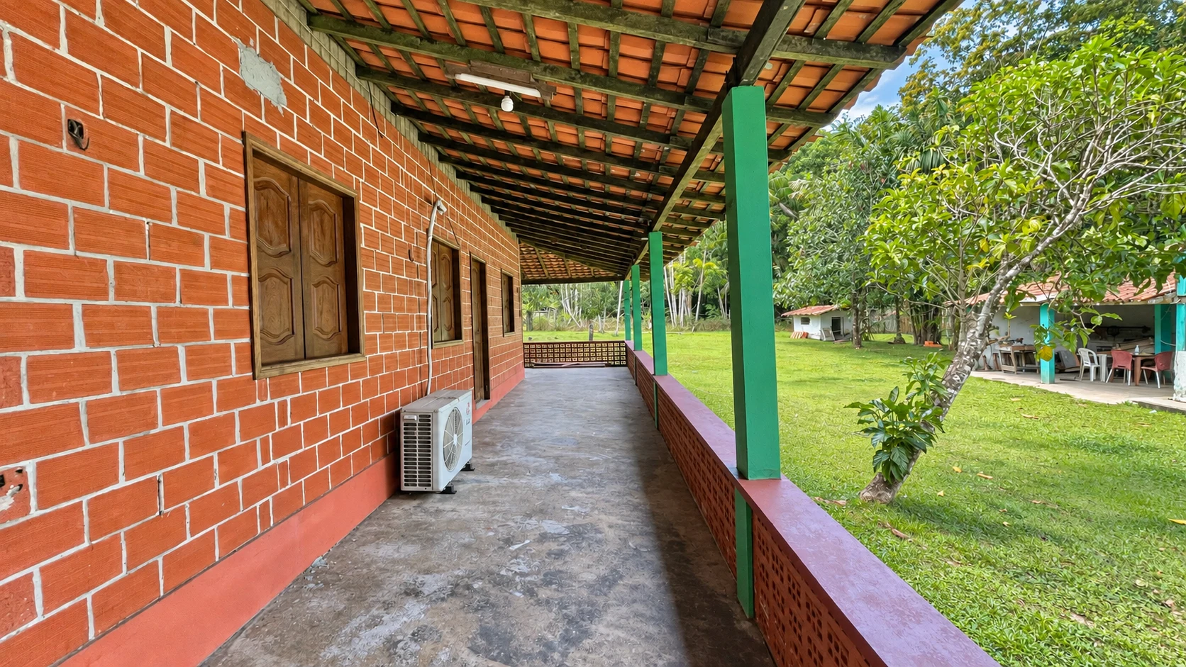 Varanda lateral coberta ao longo da fachada de tijolos da casa