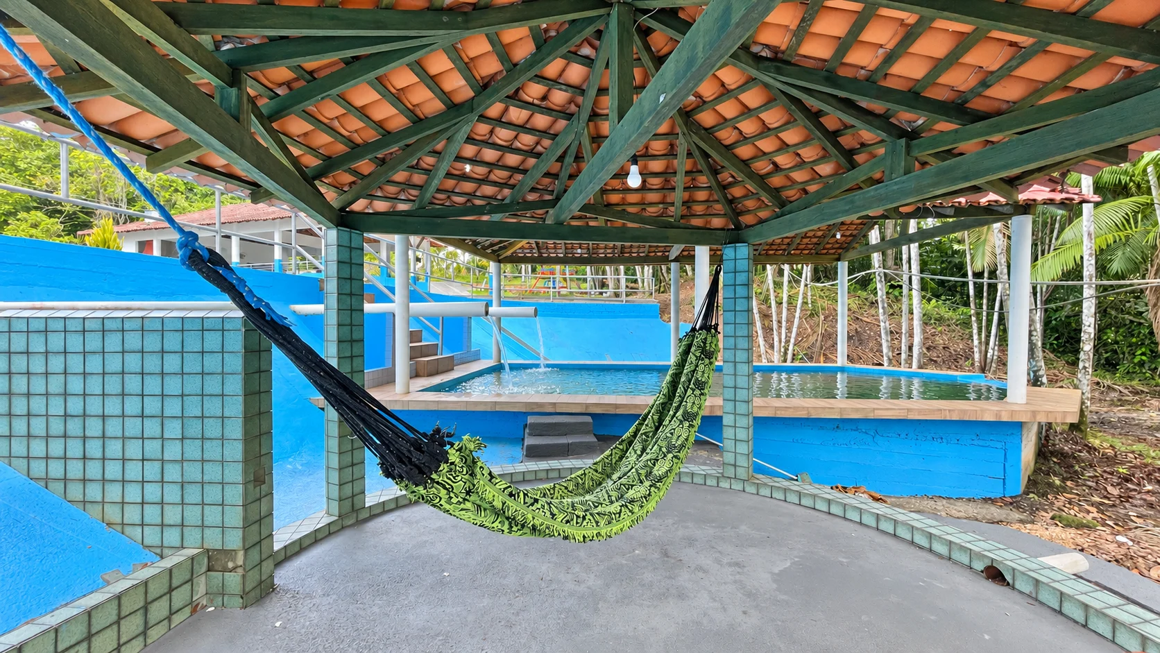 Rede sob uma cobertura com a piscina natural ao fundo